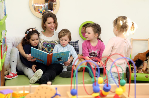 Vier Kinder lesen mit der Pädagogin ein Buch 