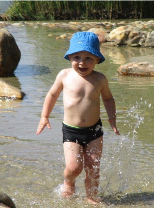 Ein kleiner Junge spielt äußerst begeistert in einem seichten Fluss