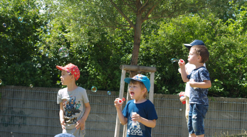 Kinder beschäftigen sich im Garten mit Seifenblasen