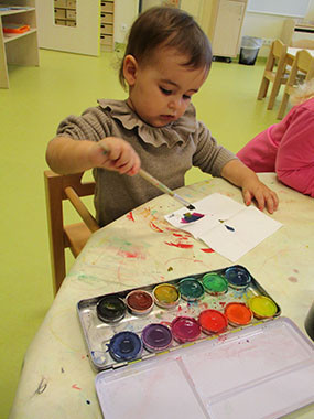 Ein kleines Mädchen gestaltet kreativ mit Wassermalfarben