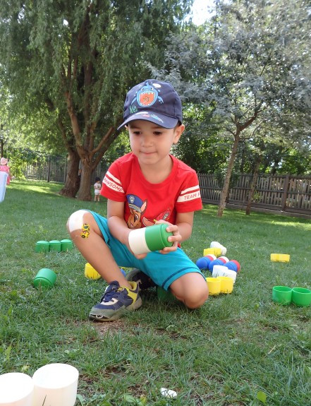 Ein Junge spielt aufmerksam mit Bausteinen im Garten
