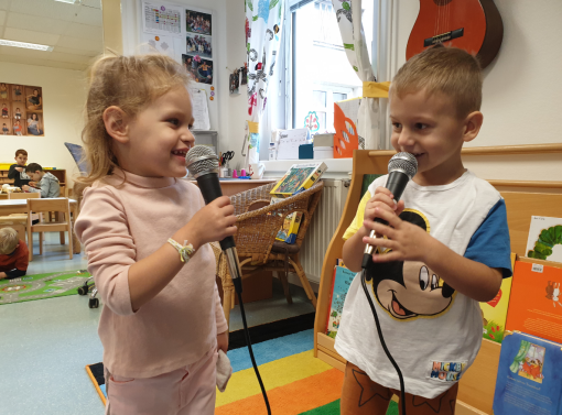 Zwei Kinder singen begeistert in Mikrofone 