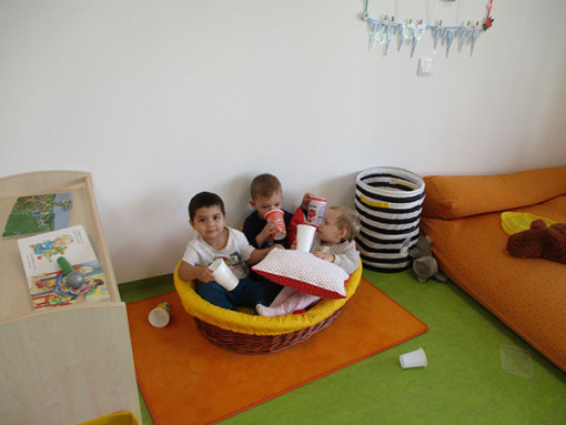Drei Kinder liegen gemeinsam in einem weich ausgelgtem Korb 