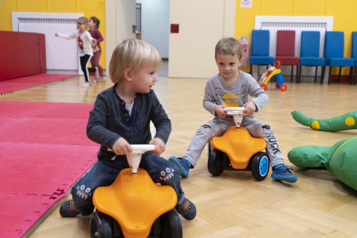 Zwei Buben auf Rutschautos fahren durch den Seversaal