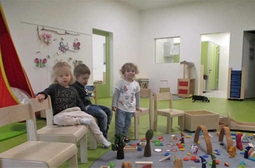 Drei Kinder betrachten gespannt kunstvolle Spiel-Objekte